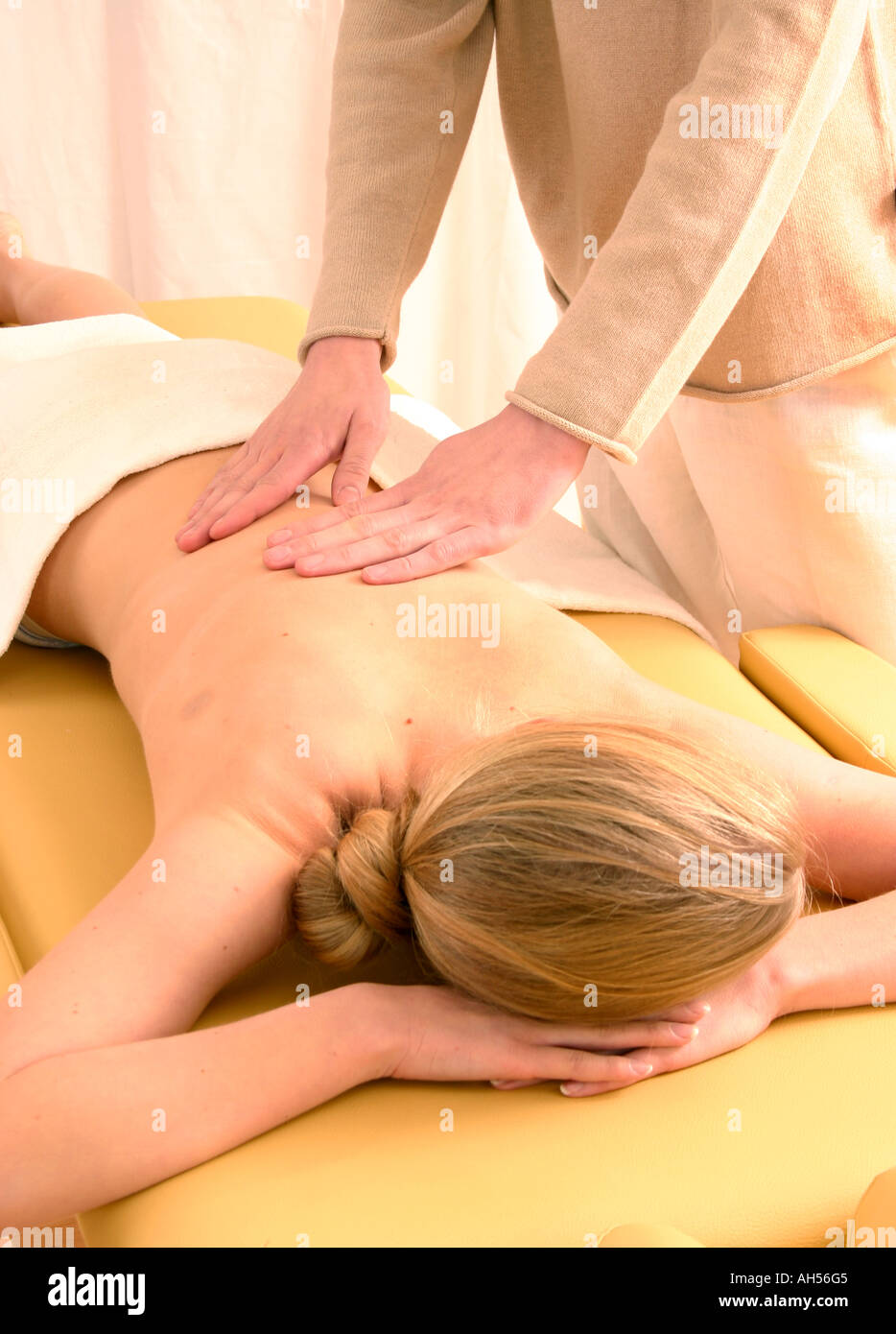 indoor cosmetics beauty care beauty salon young woman 25 30 blonde naked  back lie couch massage fragment man masseur hand han Stock Photo - Alamy