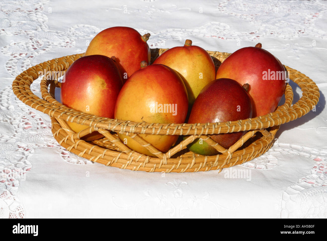 Mangoes in fruit basket on white table clothe Stock Photo