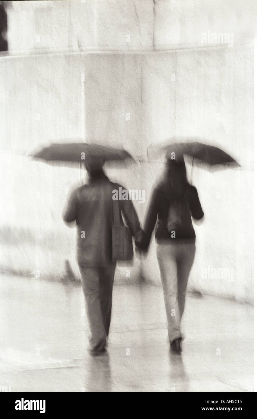 Couple walking with umbrellas Stock Photo Alamy