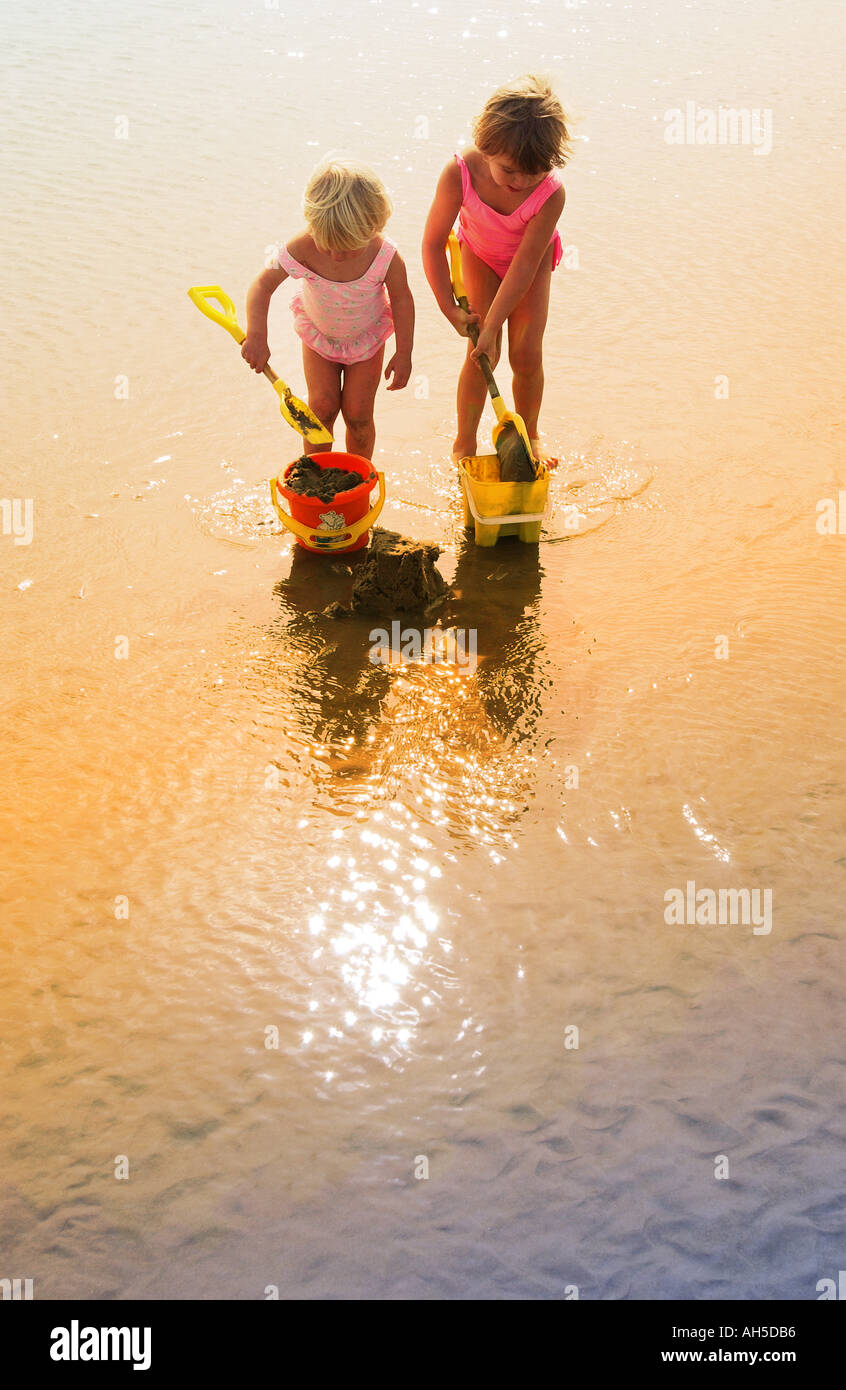 Children playing in the sand with buckets and spades hires stock