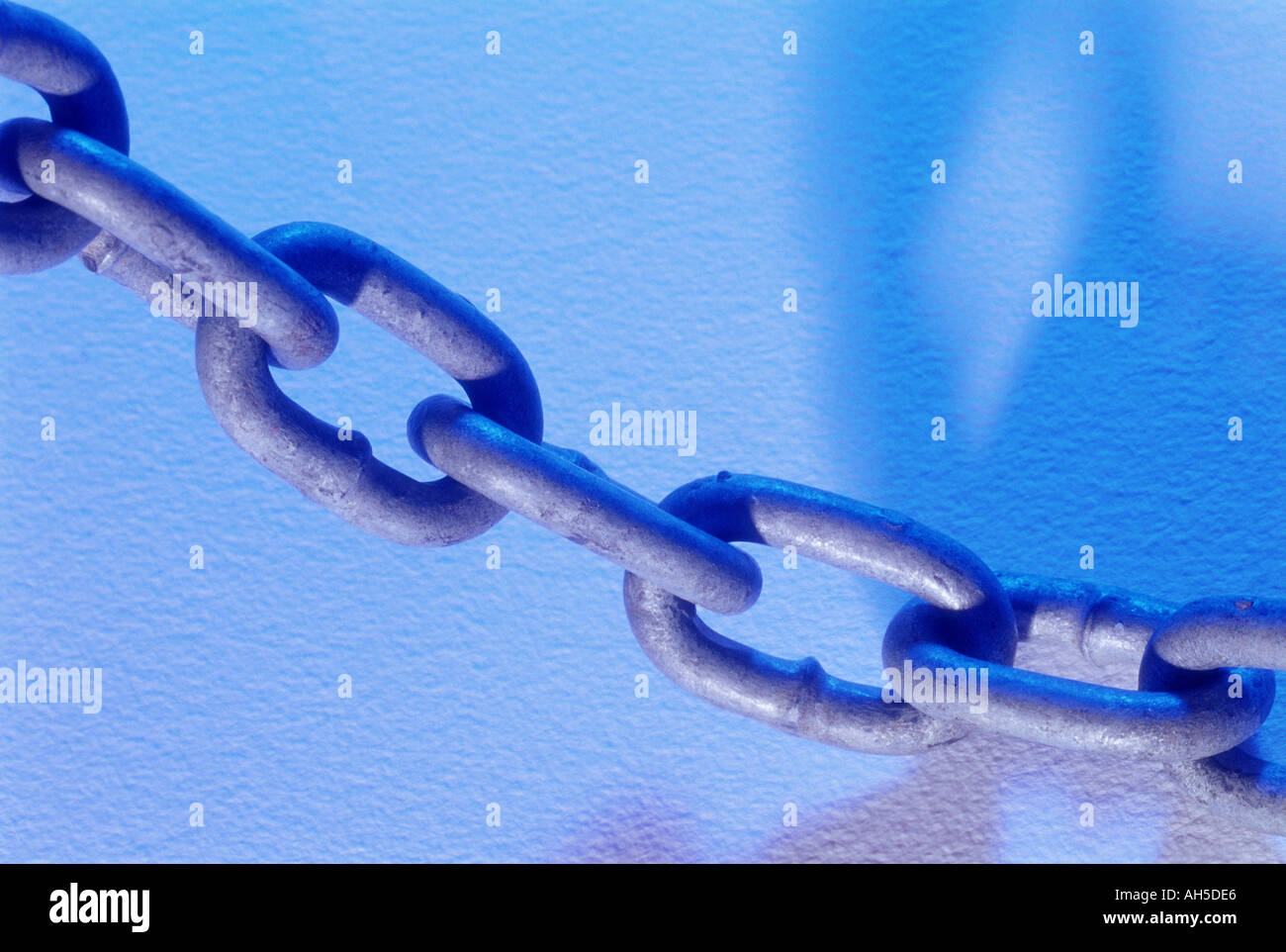 Suspended chain link against blue background with shadow Stock Photo