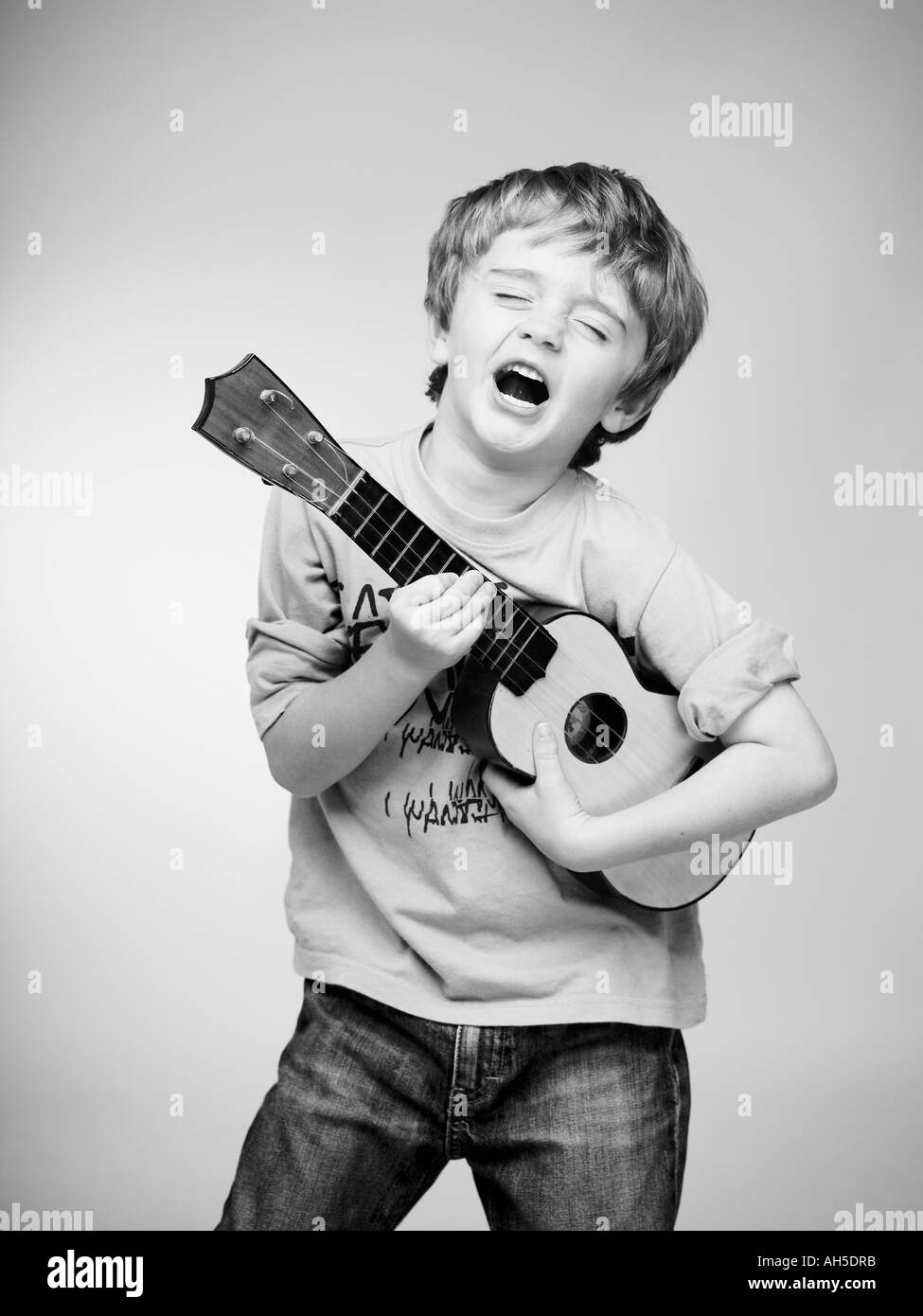 boy pretending to be a rock star with small childs guitar ukulele ukelel Stock Photo