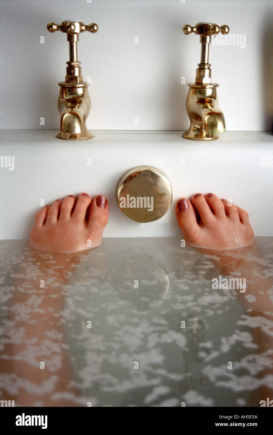 Woman s feet in bath with brass taps Stock Photo Alamy