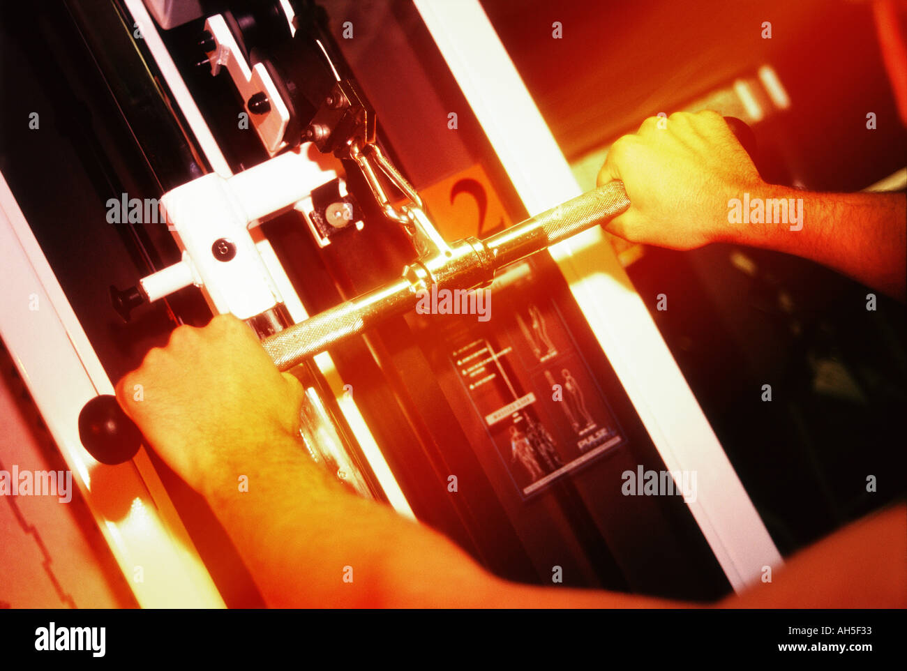 Weights machine showing arms exercising in gym warm lighting  Stock Photo
