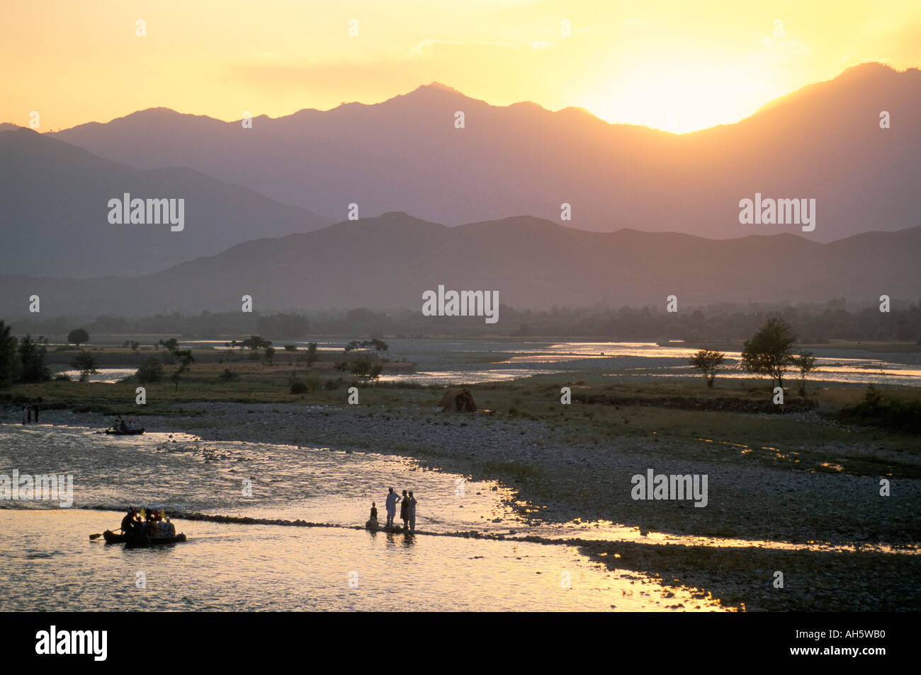 Crossing river at dusk near Mingora Swat Valley Pakistan Asia Stock Photo