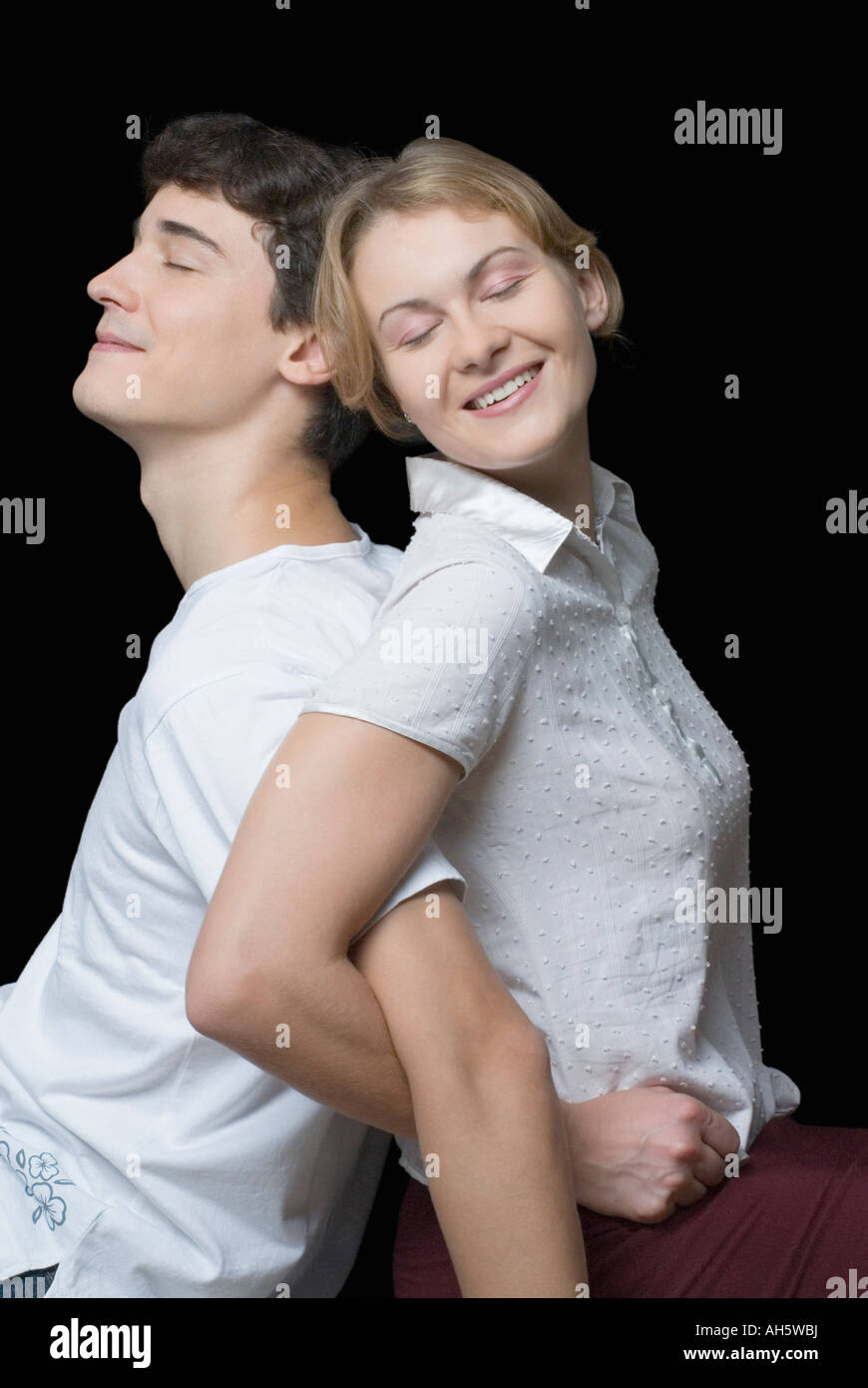 Closeup of a young couple standing back to back with their arms