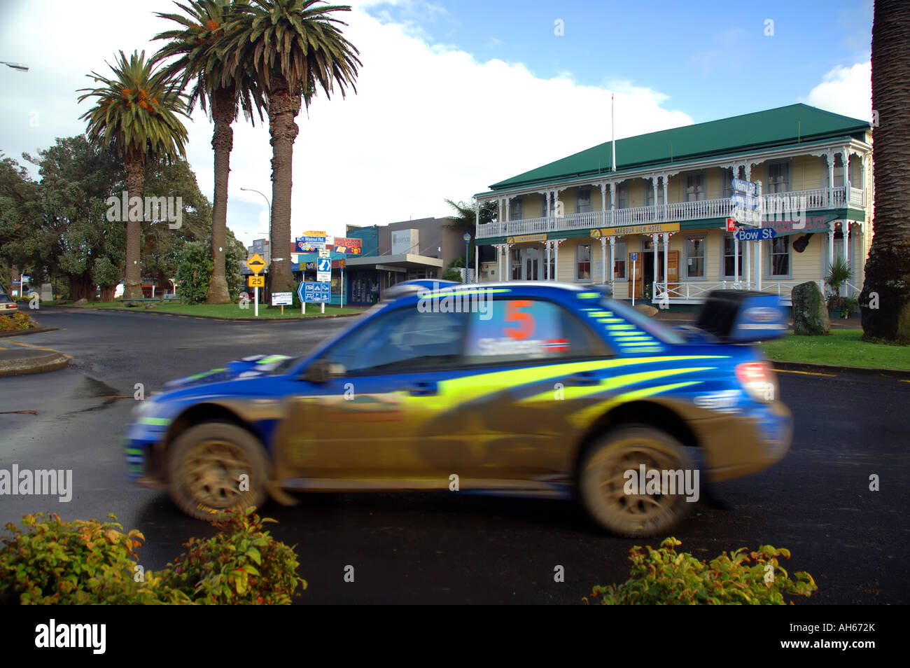 Petter Solberg's mudspattered subaru rally car streaks through sleepy coastal town of Raglan during World Rally New Zealand 2006 Stock Photo