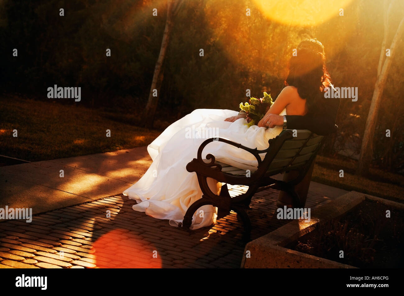 Bride and groom sitting on bench with sun going down Stock Photo - Alamy