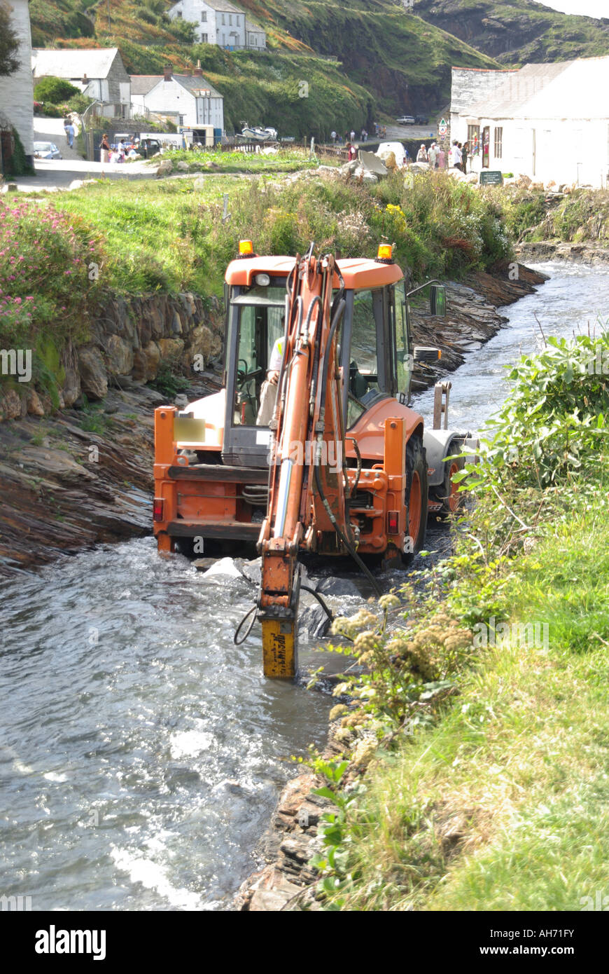 Hydraulic excavator driver at work breaking up rock to deepen & improve capacity of River Valency at Boscastle Cornwall England UK after severe flood Stock Photo
