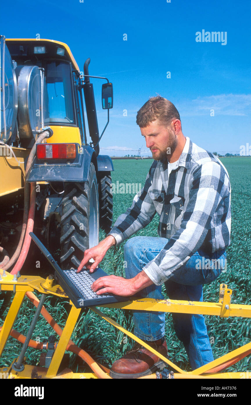 Farmer using a laptop computer in the field to calculate and record ...