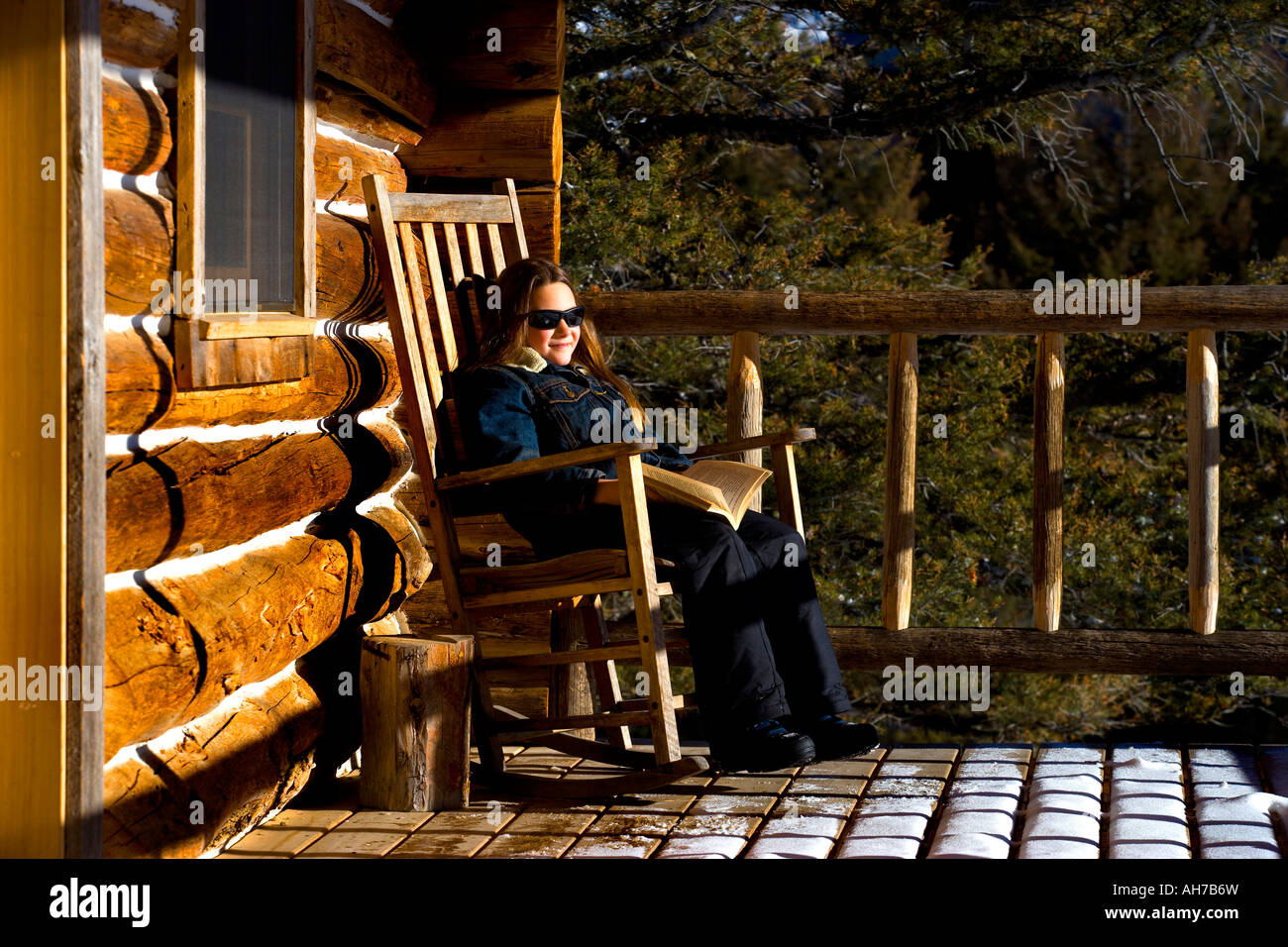 Girl sitting in a rocking chair and holding a book Stock Photo - Alamy