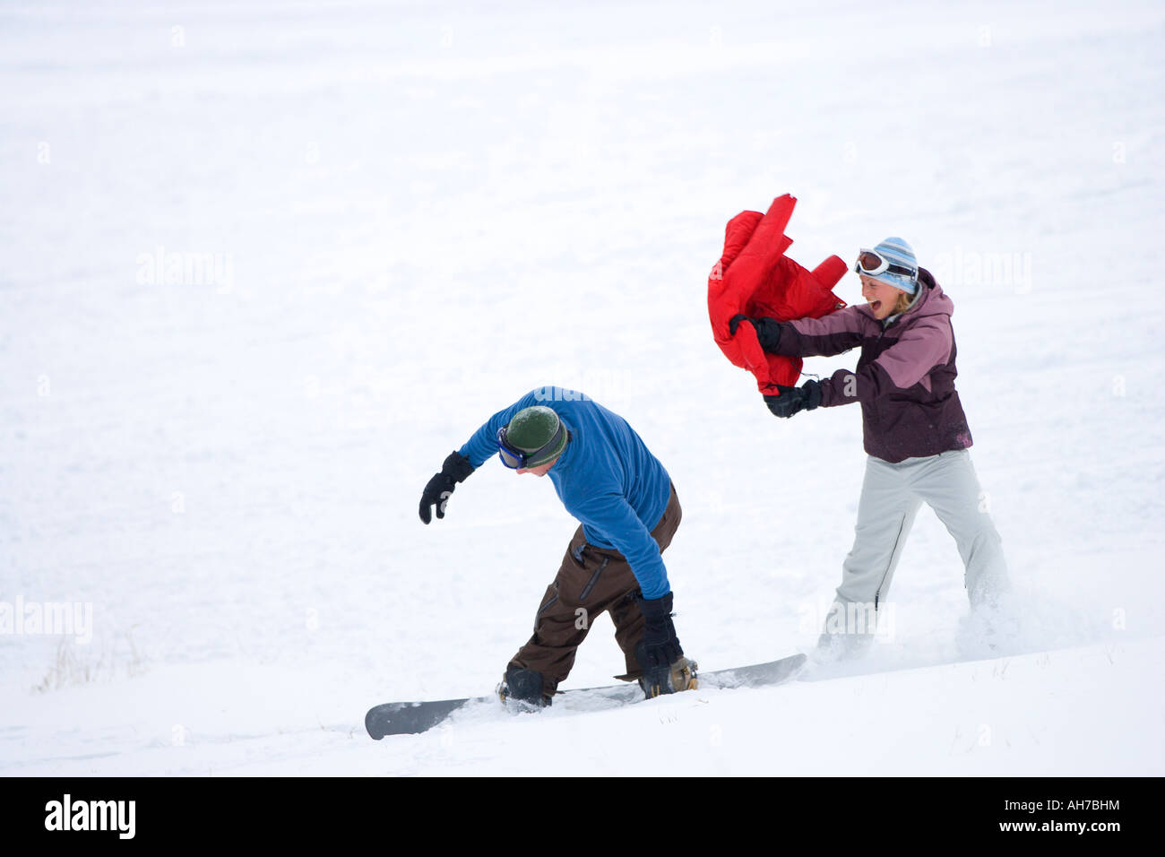 Mid adult man snowboarding past a mid adult woman Stock Photo