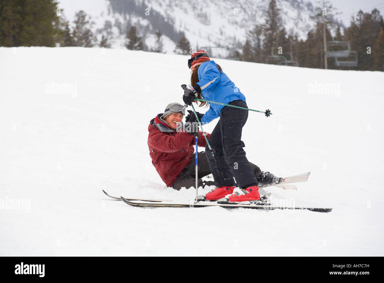 Young woman on skis helping a mid adult man Stock Photo - Alamy
