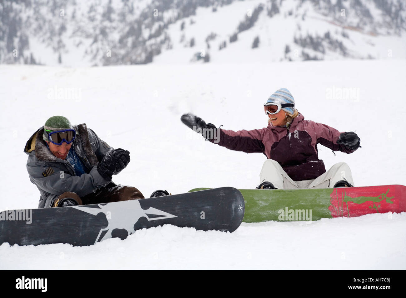 Mid adult couple sitting and throwing snowballs Stock Photo - Alamy
