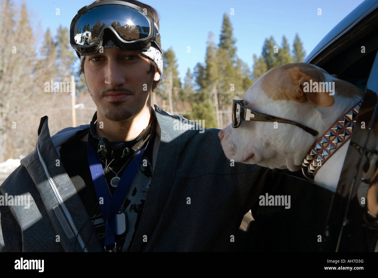 Young man beside a dog wearing sunglasses Stock Photo