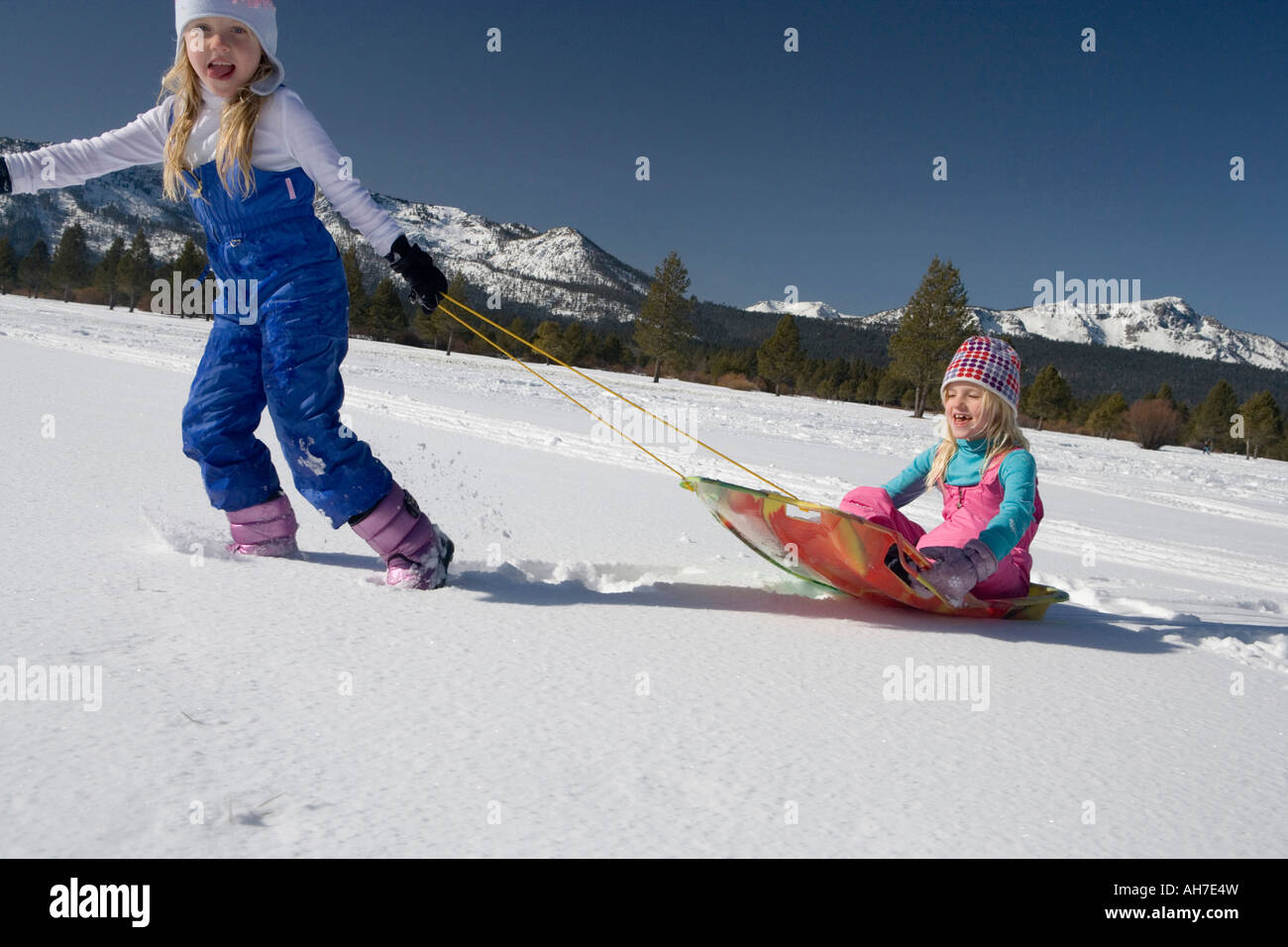 Girl pulling her sister on a sled Stock Photo