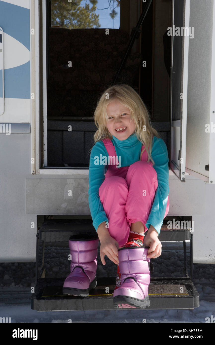 Girl sitting on the steps of a recreational vehicle and putting on her ...