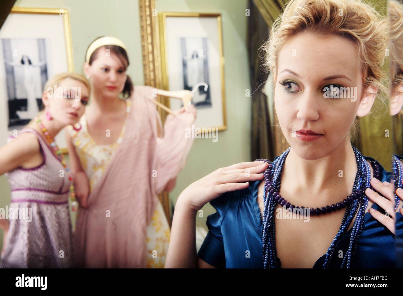 Close-up of a young woman a necklace with her two friends watching in the background Stock Photo