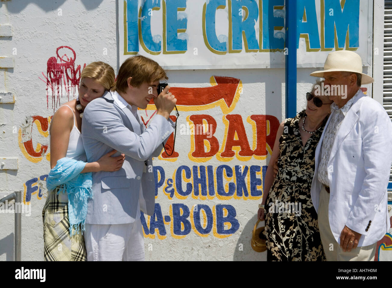 Young woman standing behind a young man photographing a senior couple Stock Photo