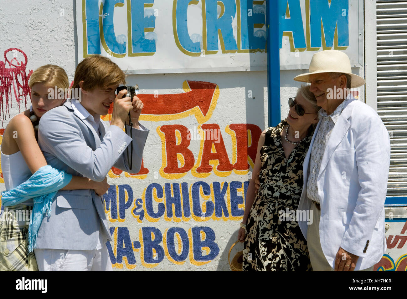 Young woman standing behind a young man photographing a senior couple Stock Photo