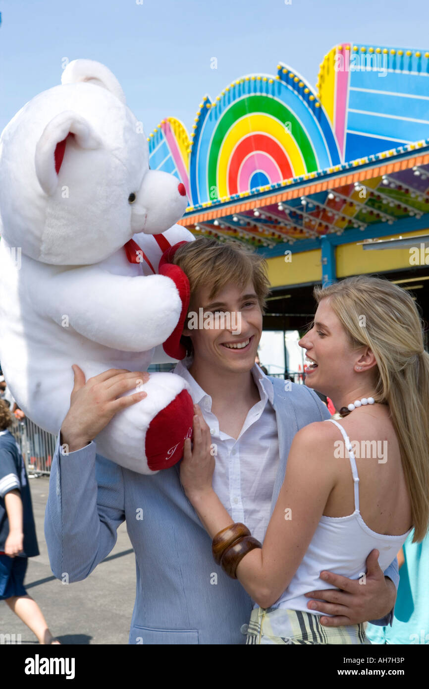 Young man holding a stuffed animal and embracing a young woman Stock Photo