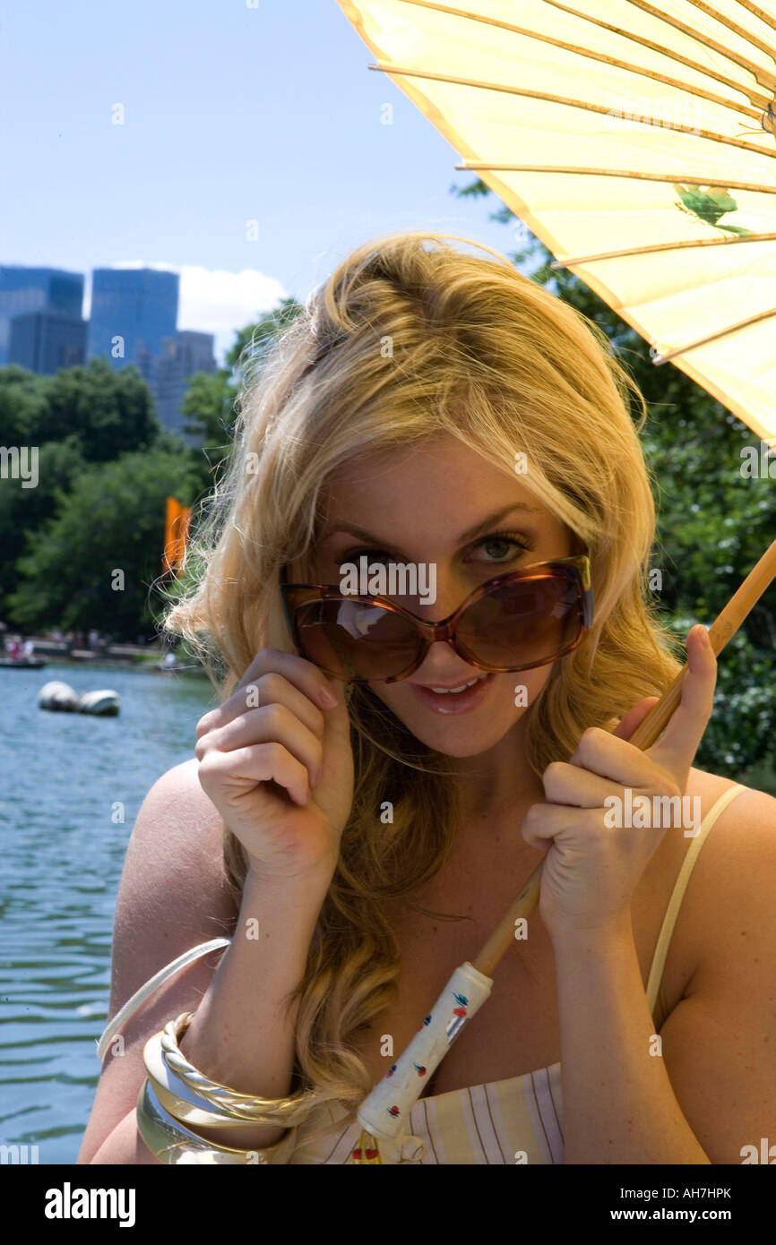 Portrait of a young woman peering over sunglasses and smiling Stock Photo