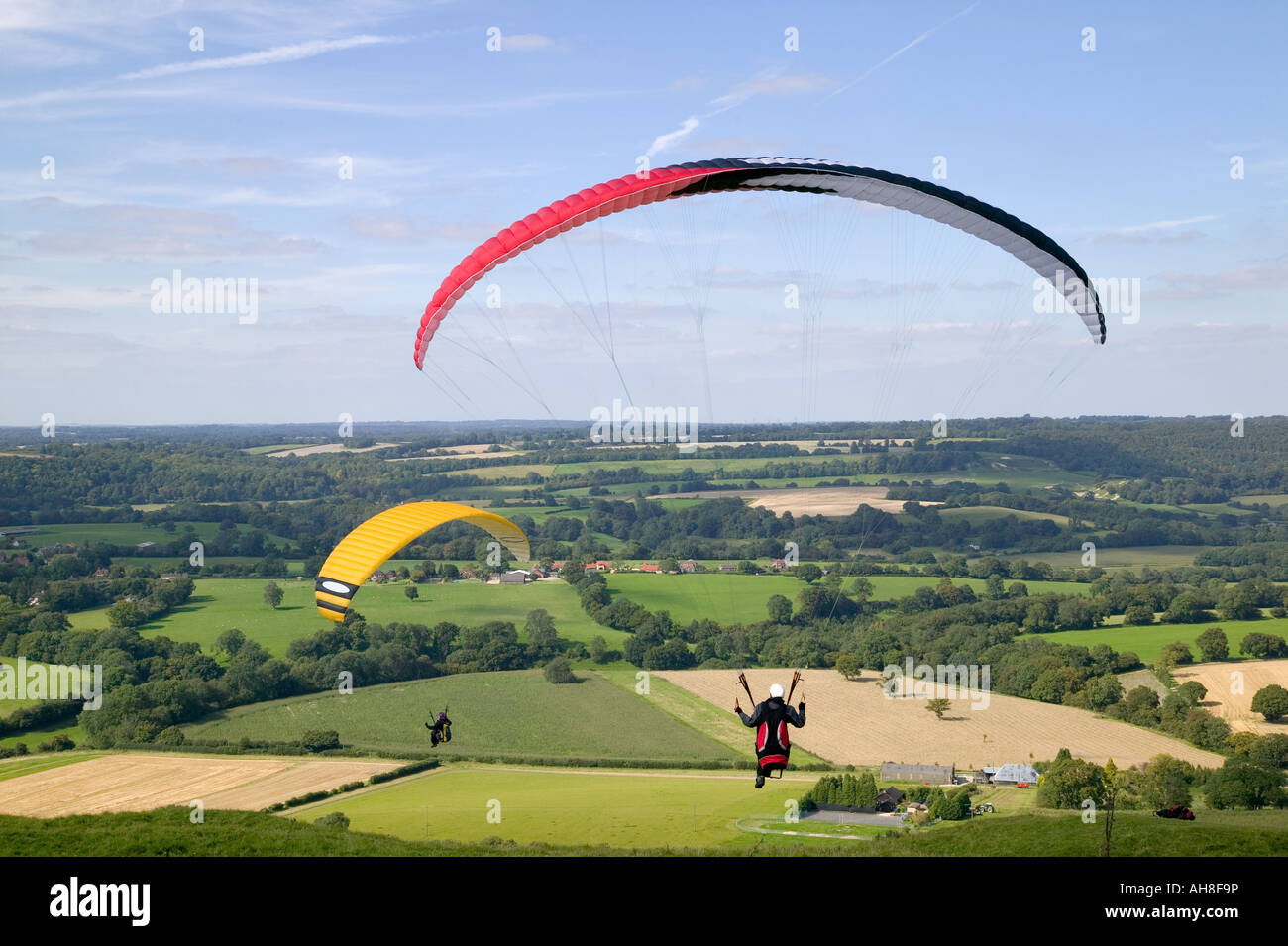 Two paragliders flying across a rural scene Stock Photo