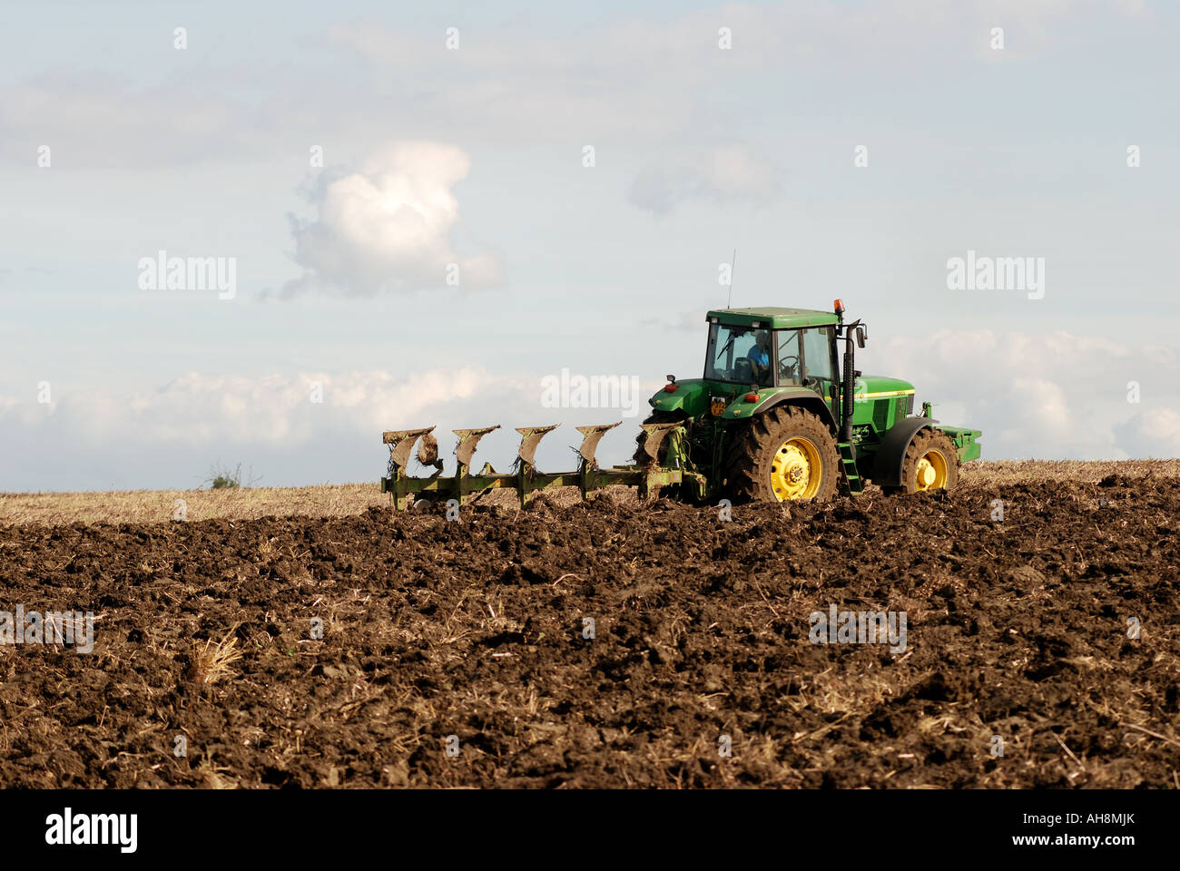 John Deere tractor ploughing stubble field, Warwickshire, England, UK