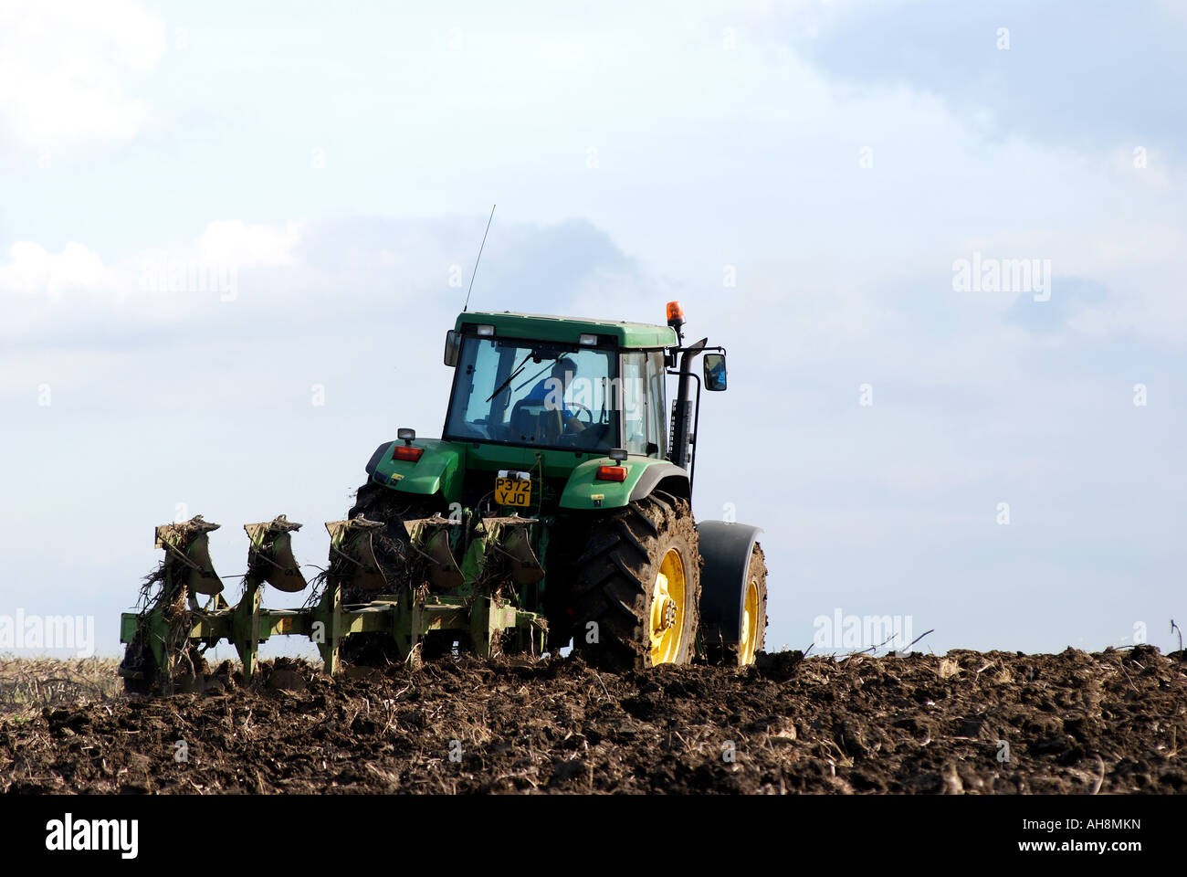 John Deere tractor ploughing stubble field, Warwickshire, England, UK