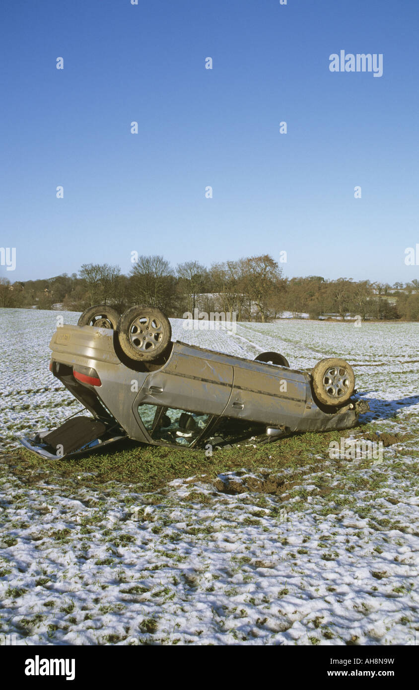 Upturned crashed car in snowy field Stock Photo