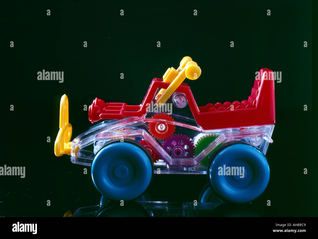 AAD71613 Toy car automobile auto childs joy show piece made of colourful plastic blue green yellow red colours black back ground Stock Photo