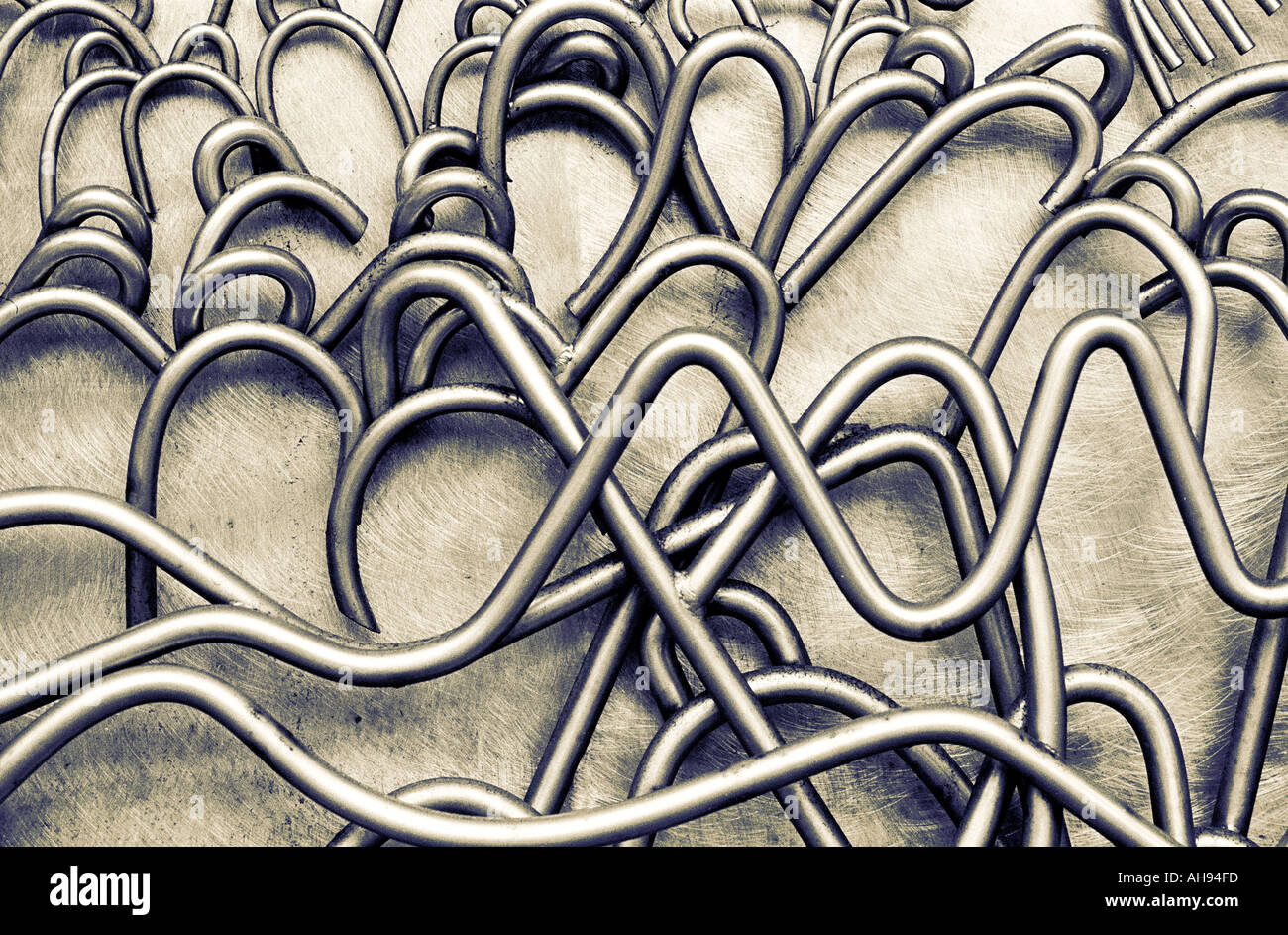 Twisted and curved carved metal tubing like cables on reflective metal surface Stock Photo