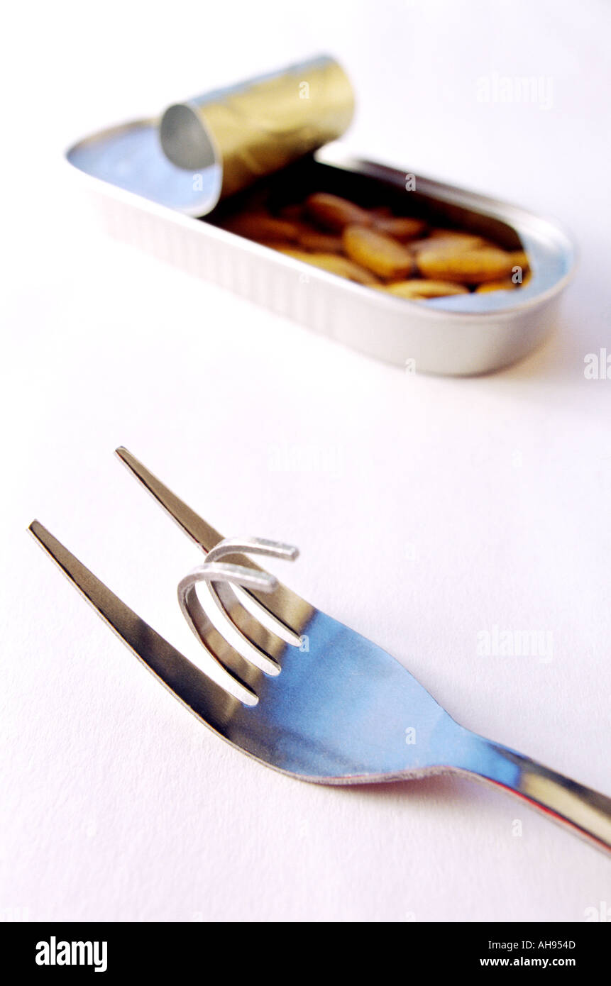 Bent curved fork in foreground tin can with vitamins with lid rolled