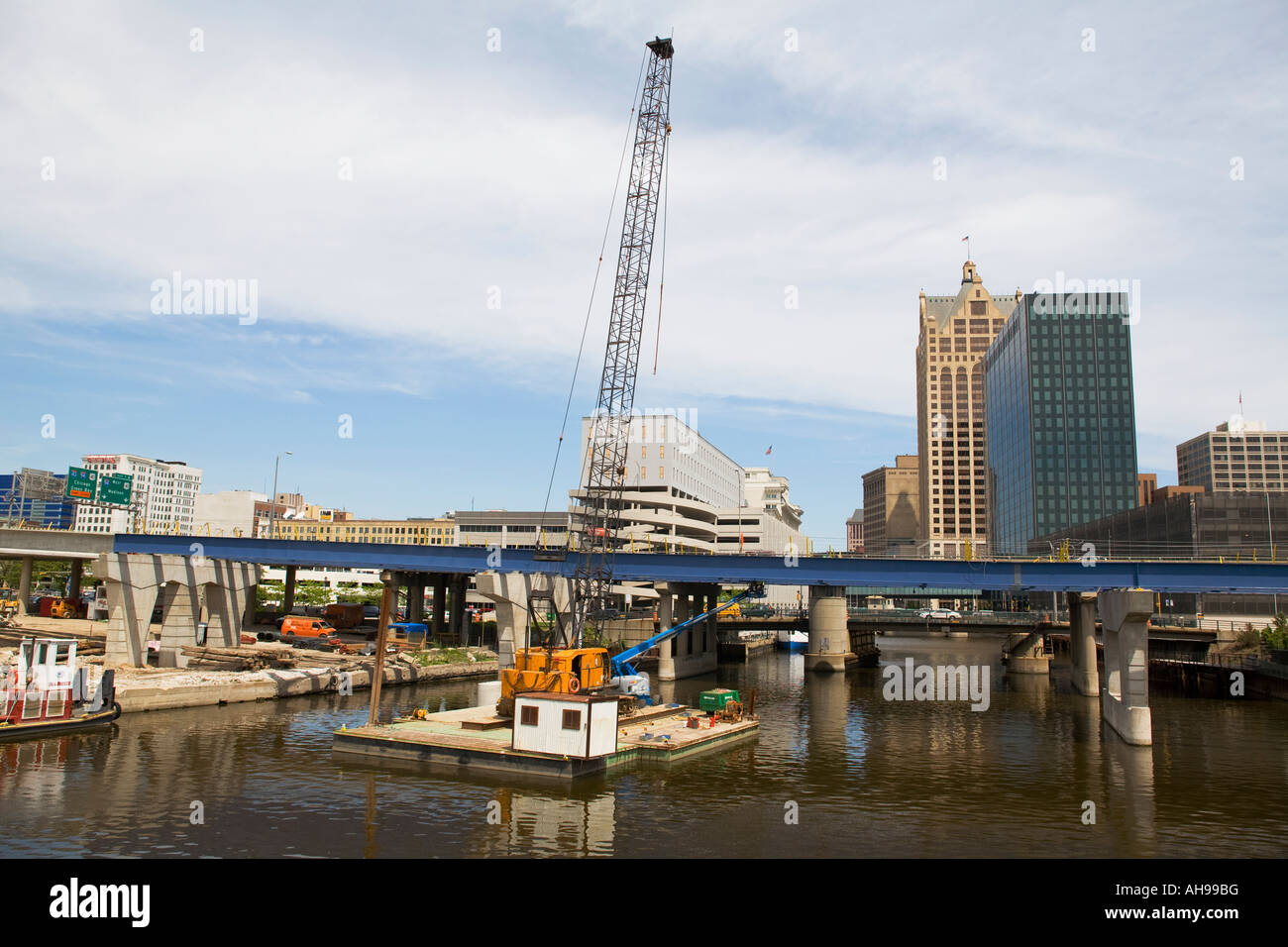 WISCONSIN Milwaukee Crane on barge in Milwaukee River bridge construction project over river downtown buildings Stock Photo