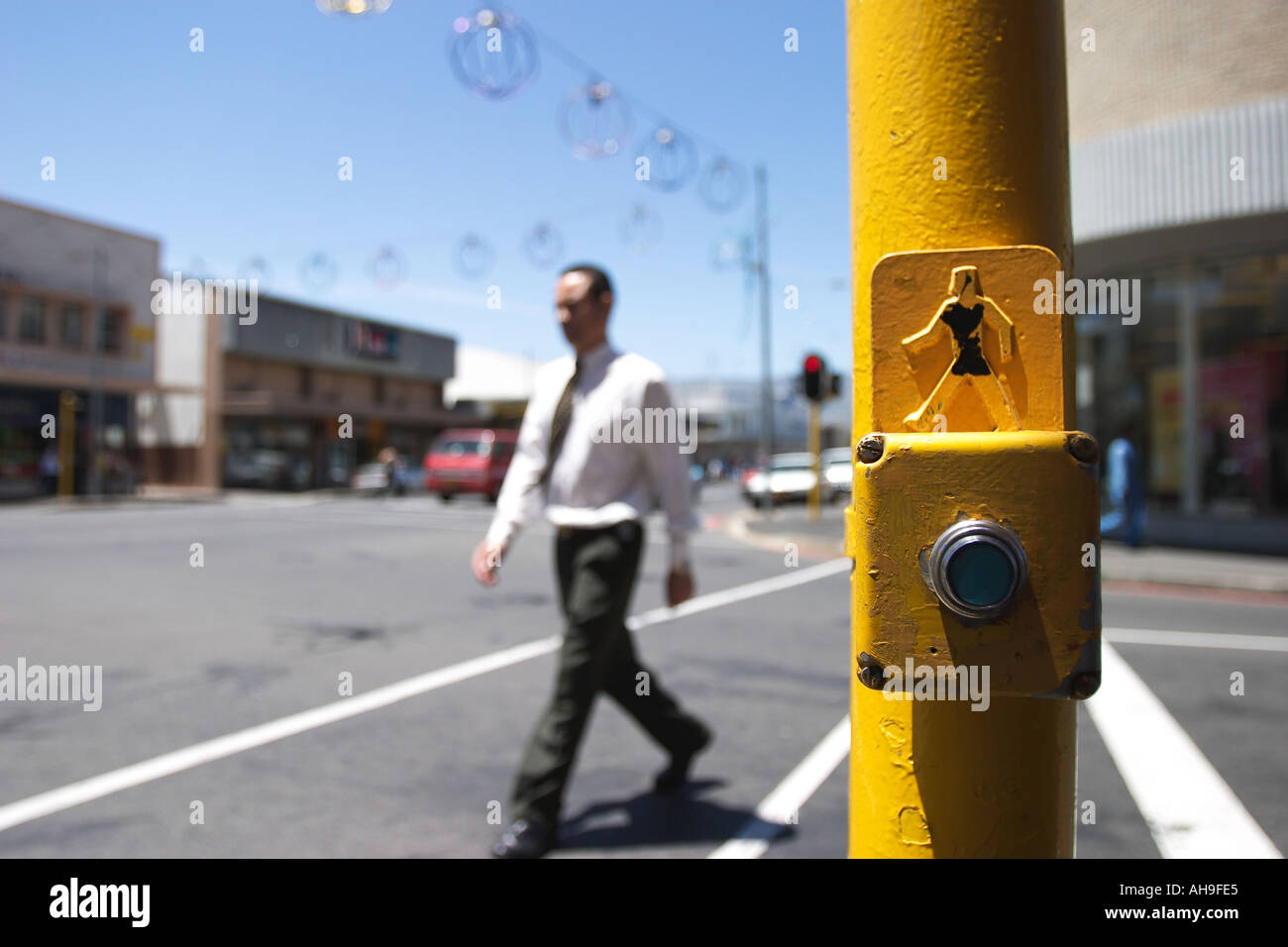 Crosswalk with yellow car stop button and a businessman crossing Paarl South Africa Stock Photo