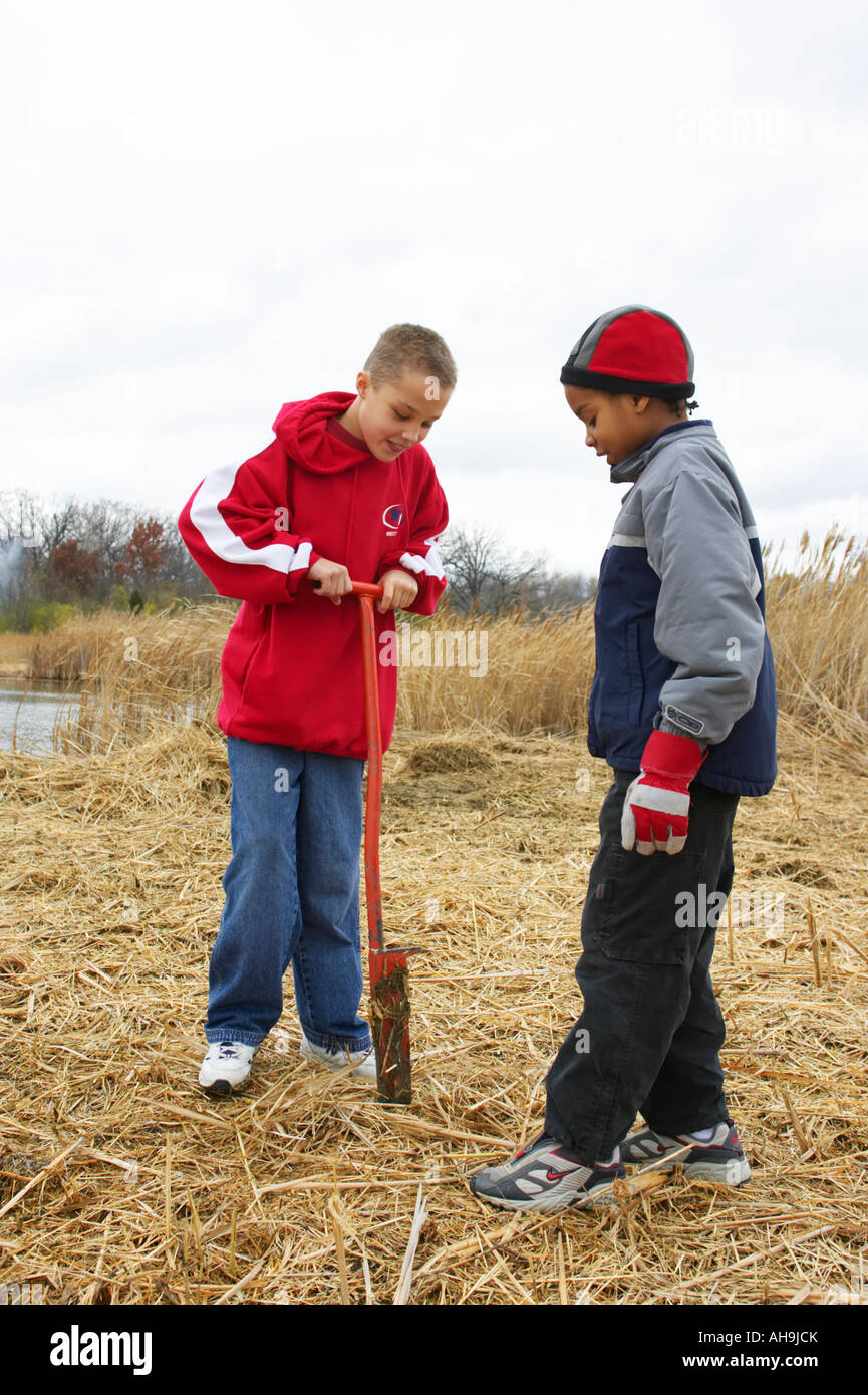 ILLINOIS Vernon Hills Two boys use spade to prepare hole for tree planting environmental restoration project Stock Photo
