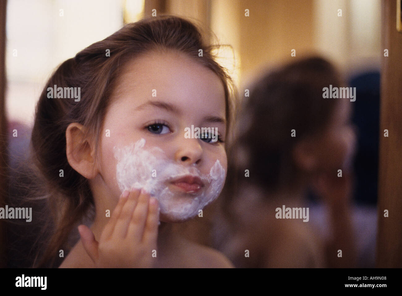 Young girl looking in mirror putting on shaving cream Stock Photo Alamy
