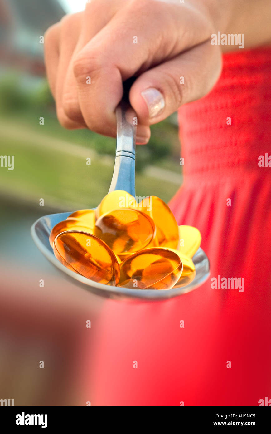 Hand holding gelcaps on spoon Stock Photo