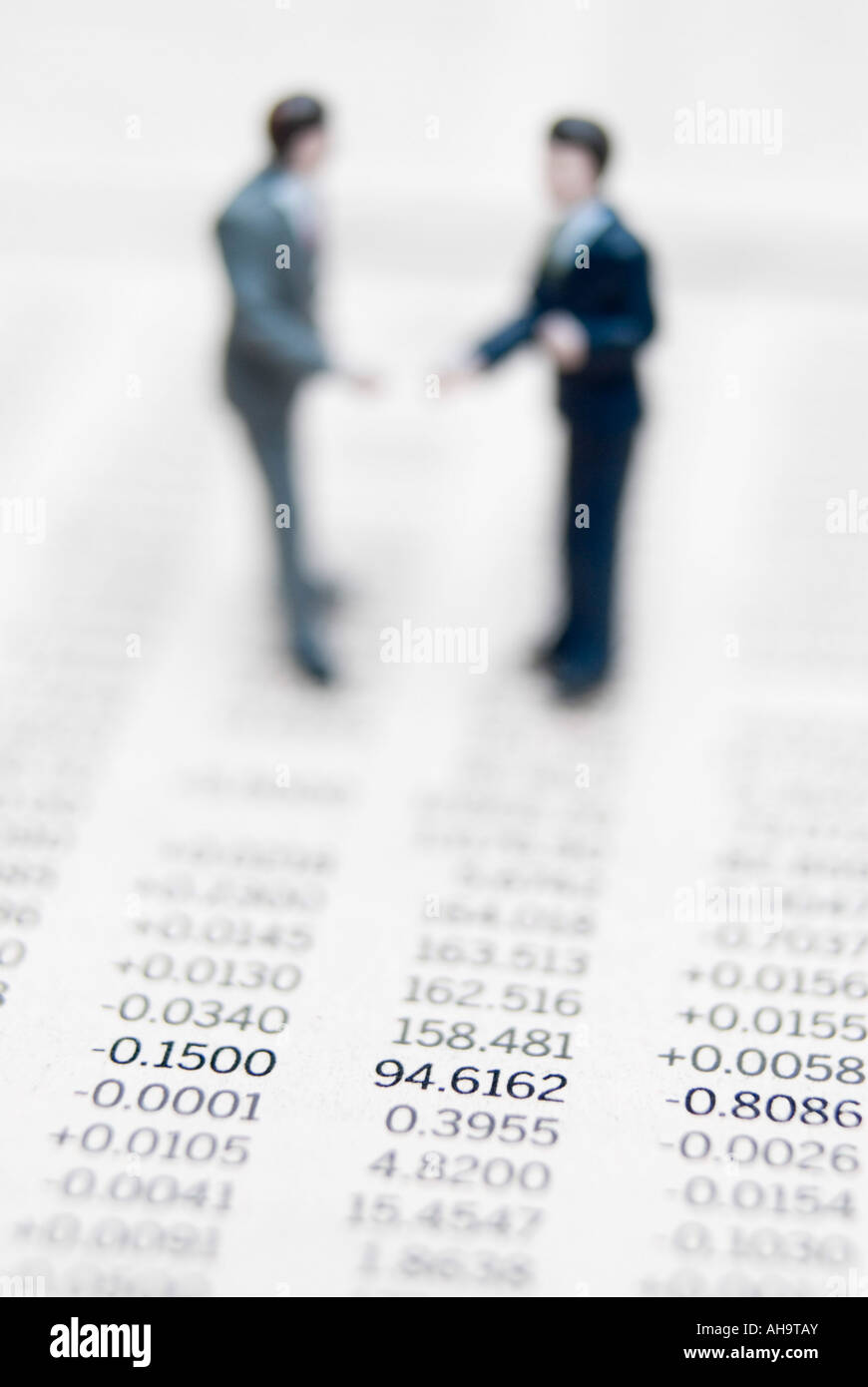 Businessmen standing on share prices shaking hands Stock Photo