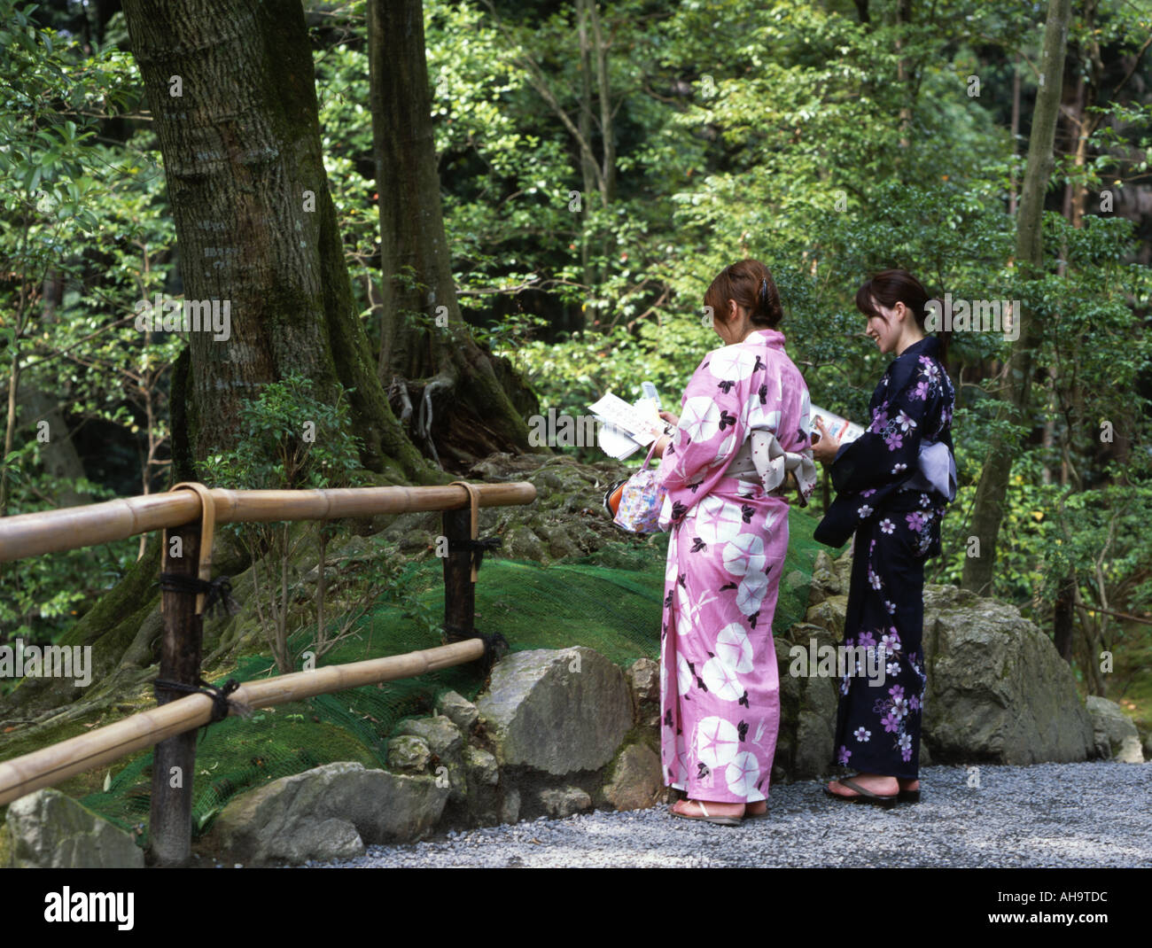 Japanese women in kimonos stand in the garden of Kinkakuji Temple Stock Photo