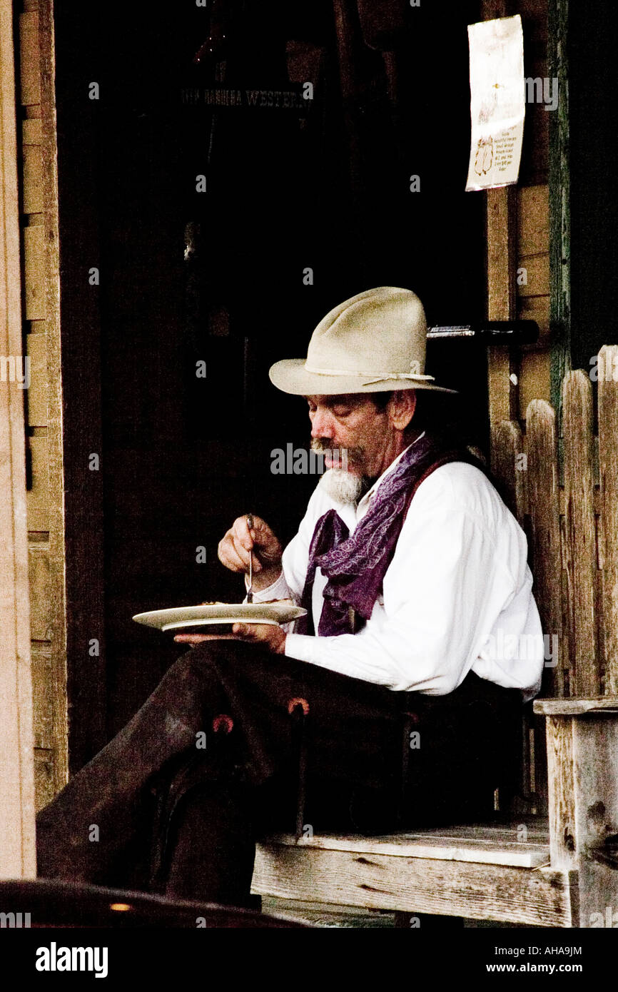 Cowboy eats meal outside store on bench in Bandera Texas USA Stock Photo