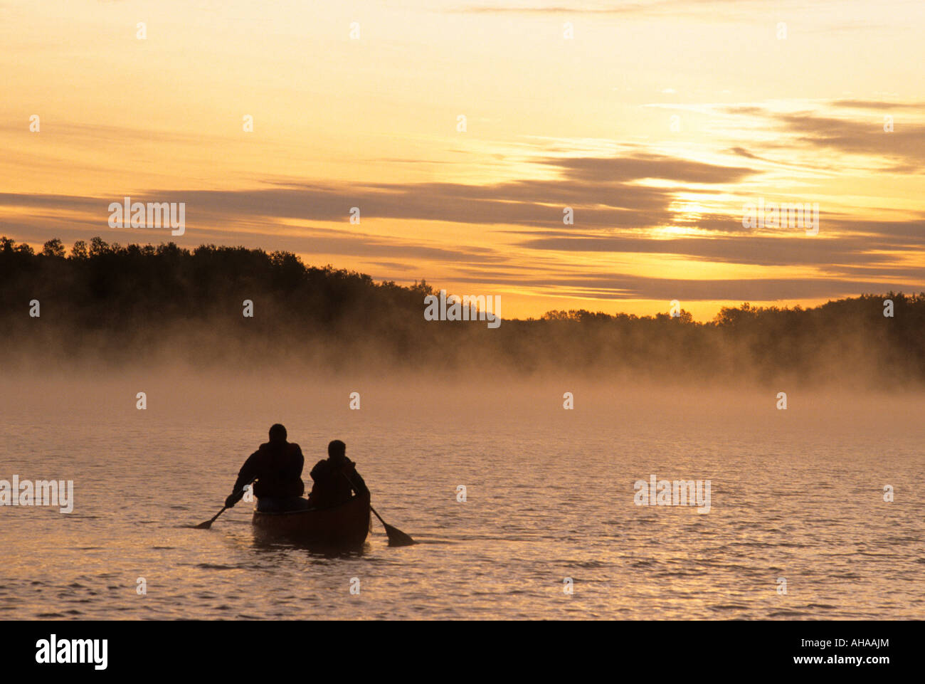 FATHER AND SON CANOE AT SUNRISE ON FALL LAKE, BOUNDARY WATERS CANOE AREA WILDERNESS, SUPERIOR NATIONAL FOREST,NORTHERN MINNESOTA Stock Photo