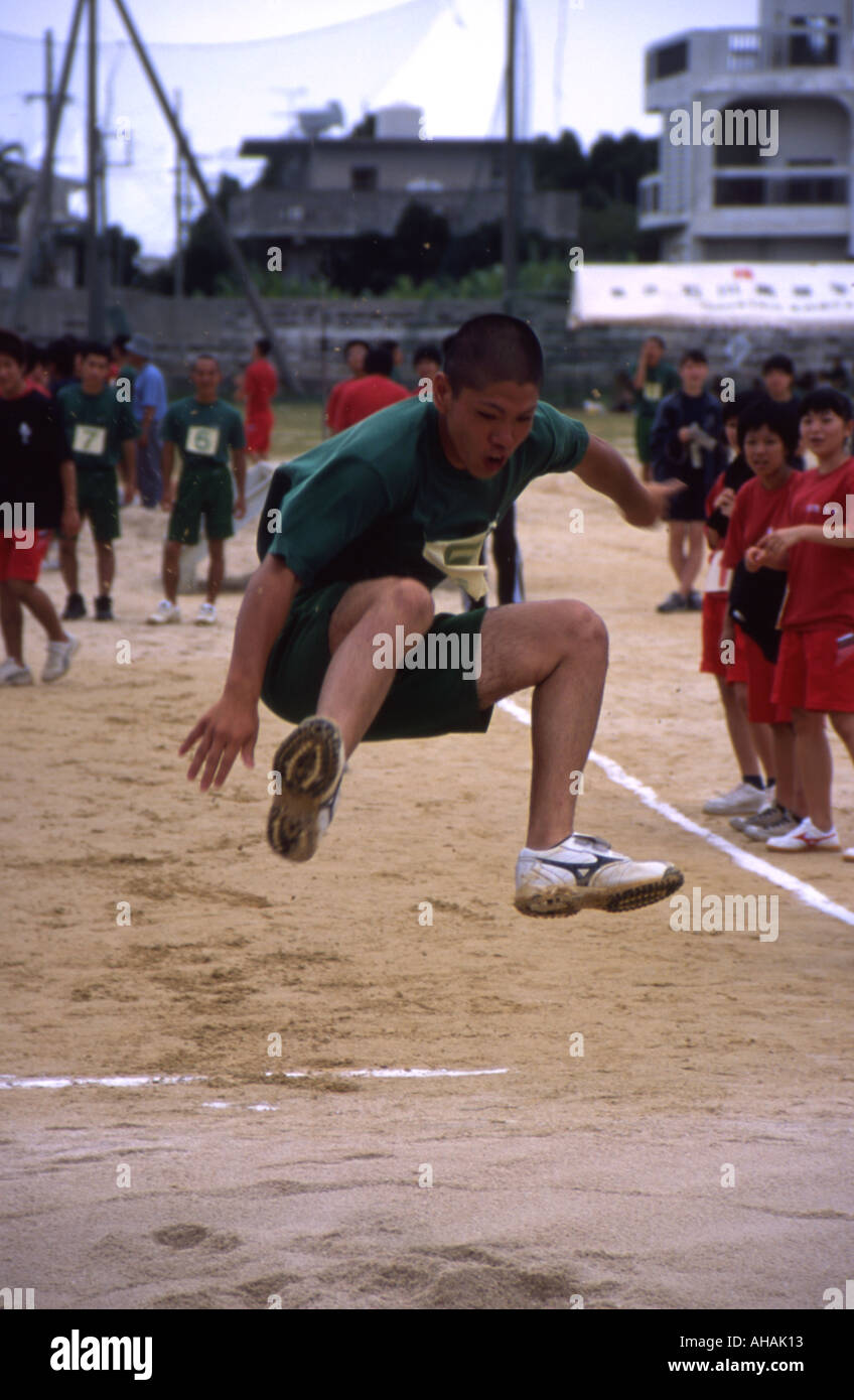 Japanese high school boy competes in the long jump during his school