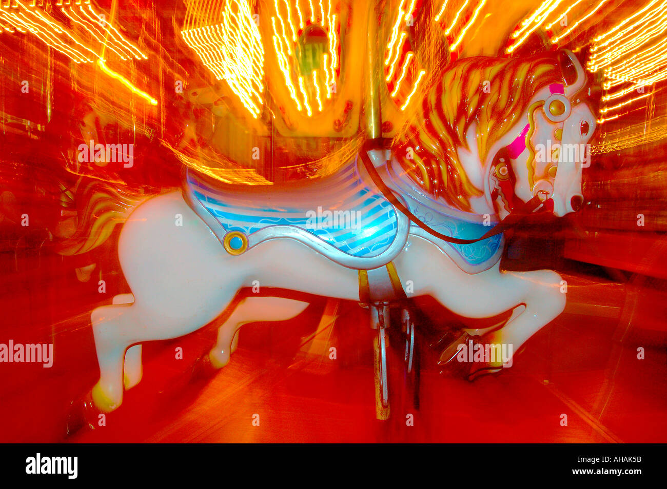 A coursel horse wildly lit spinning at a fun zone carnival Stock Photo