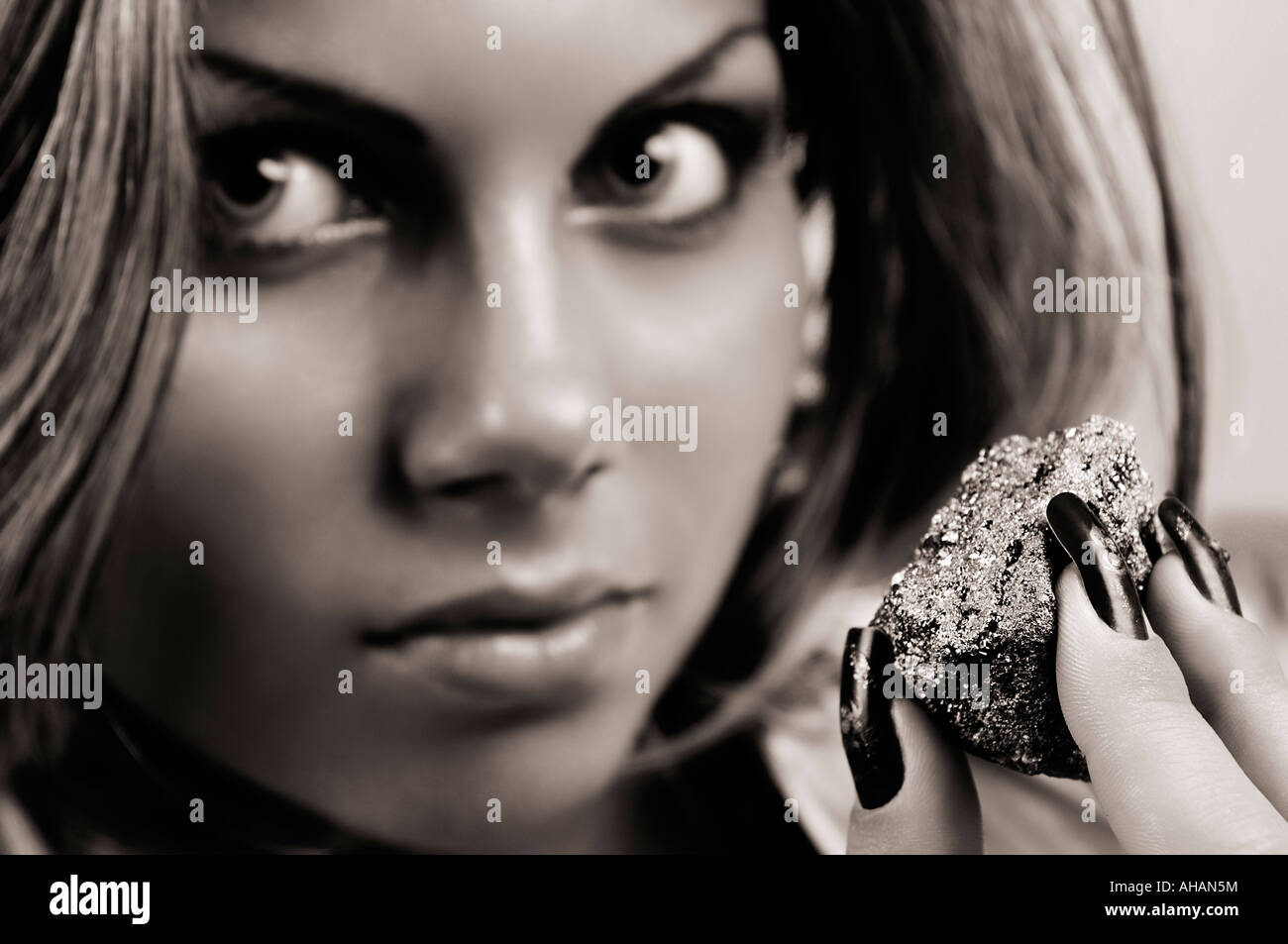 Woman with expressive eyes and hypnotized possessed look holding a shiny piece of pyrite Stock Photo