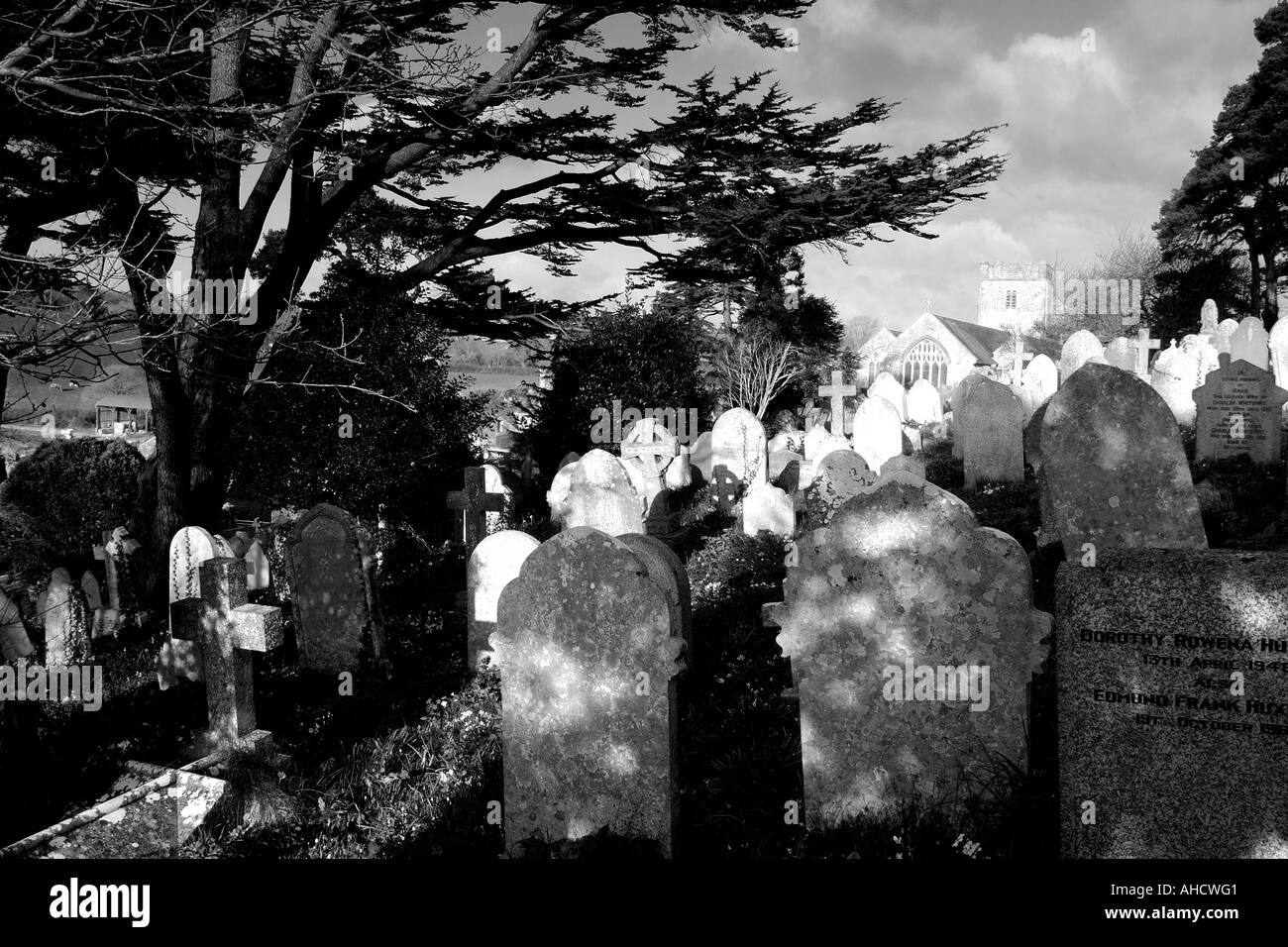 High contrast mono image of churchyard with early morning sunlight illuiminating the church as if glowing Stock Photo