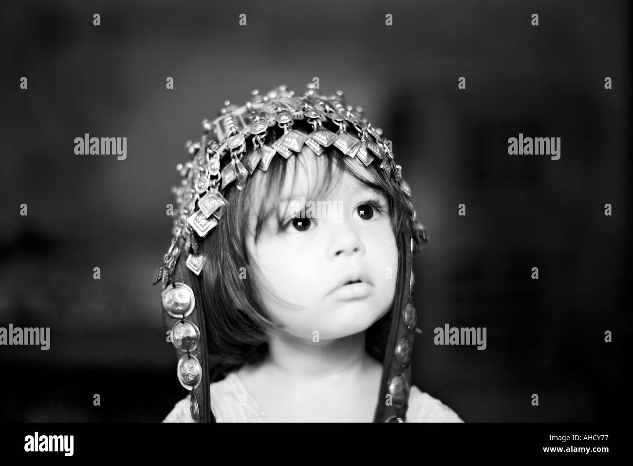 Black and white picture of a beautiful two year old girl who wears a Hunza hat and looks up to the right Stock Photo