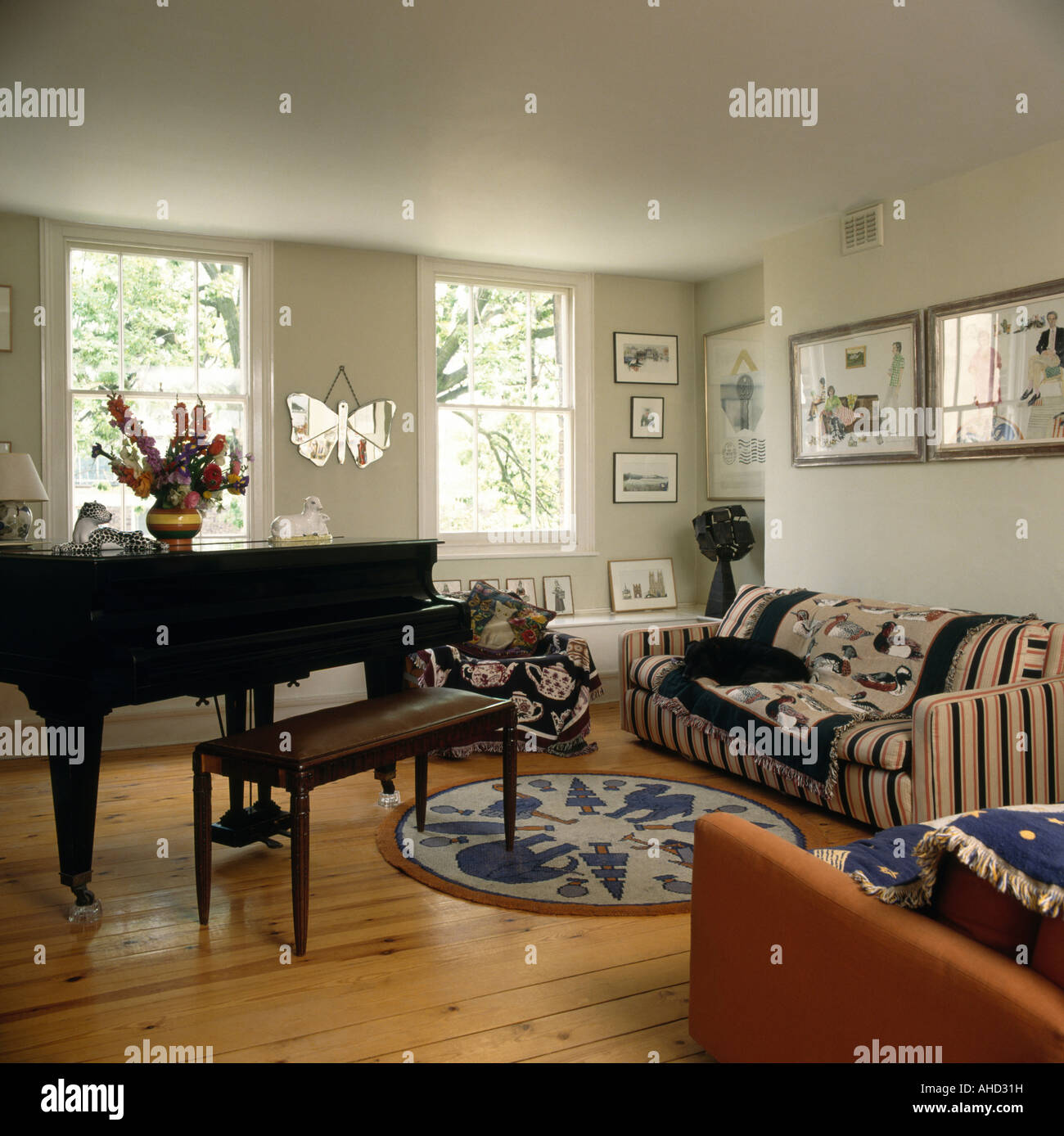Grand piano in eighties living room with patterned rugs on striped sofa and  wooden floor Stock Photo - Alamy