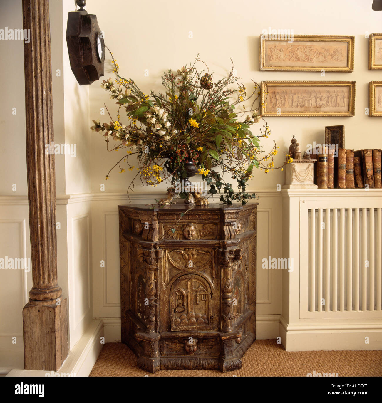 Informal flower arrangement on antique carved wooden cupboard in cream