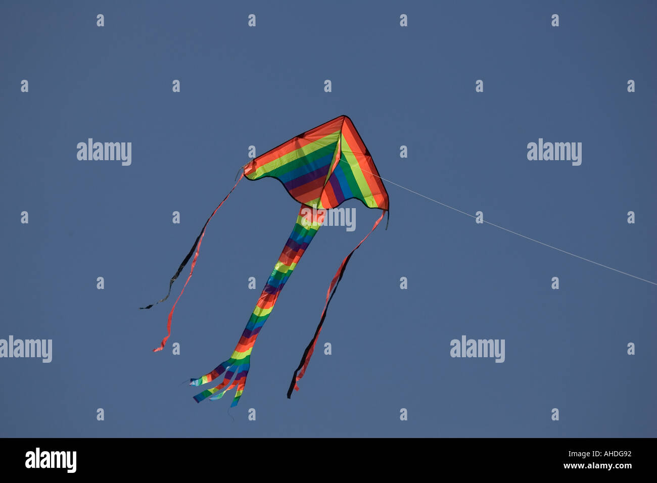 Colourful childs kite flying high in blue sky UK Stock Photo